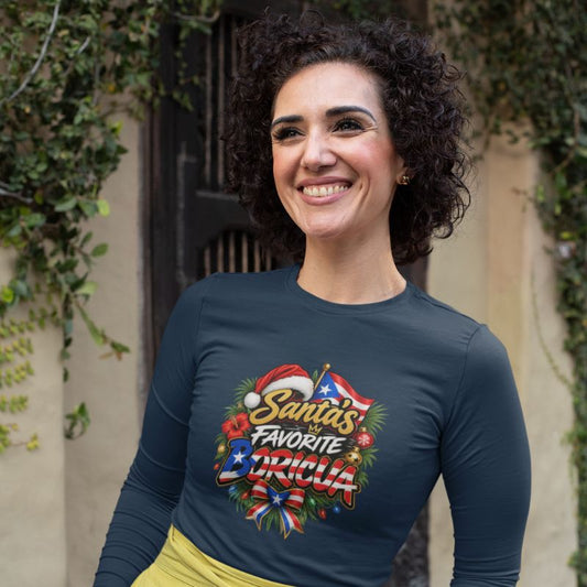 Smiling woman wearing a navy Santa’s Favorite Boricua Christmas long-sleeve shirt, standing outdoors near greenery.