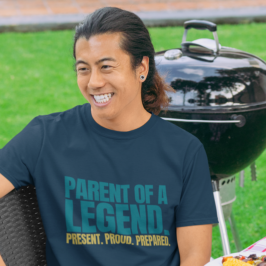 Man wearing Parent of a Legend navy tee smiling at outdoor graduation celebration
