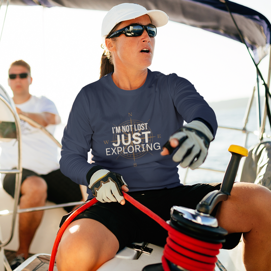 Man and woman on sailboat wearing navy I'm Not Lost Just Exploring long sleeve compass graphic tee — lifestyle shot