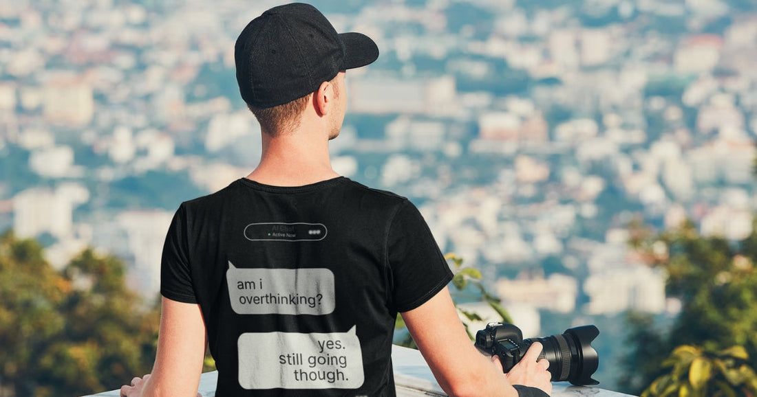 Man wearing black AI Chat Gone Wild graphic tee standing outdoors overlooking city skyline — Chat Gone Wild collection by Leela's Ink