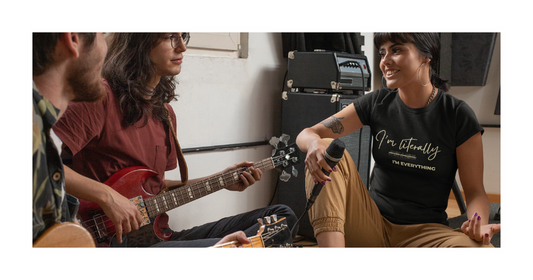 Three people spending time together indoors, including one person playing an acoustic guitar and another wearing a black graphic t-shirt.