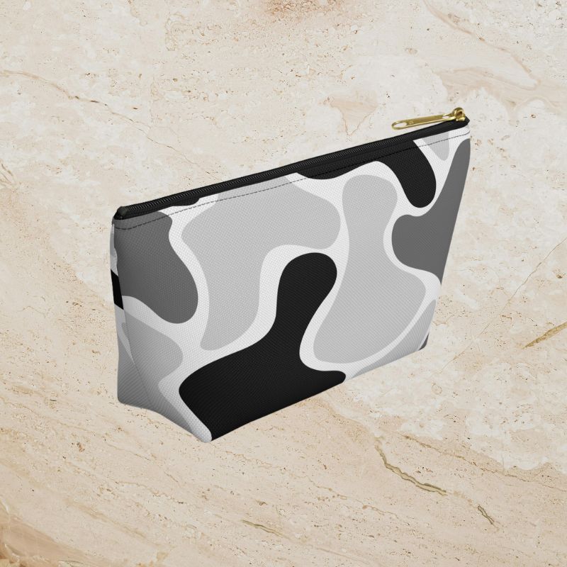 Another angled view of the black, gray, and white pouch on a warm stone surface.