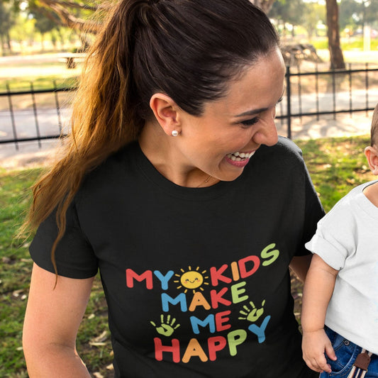 Woman smiling wearing black My Kids Make Me Happy rainbow graphic tee outdoors
