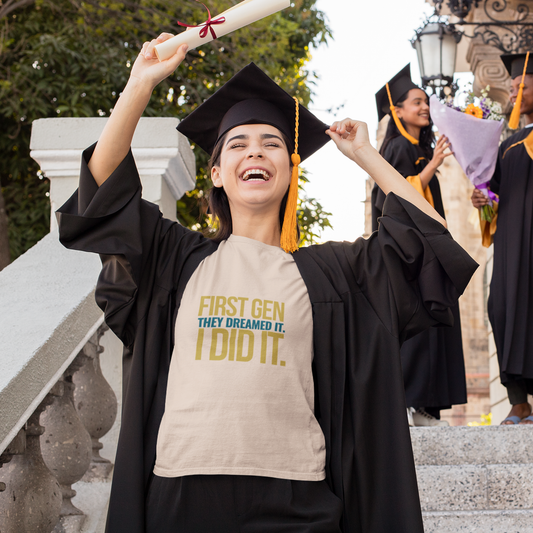 Graduating student in cap and gown with a t-shirt celebrating achievement outdoors.