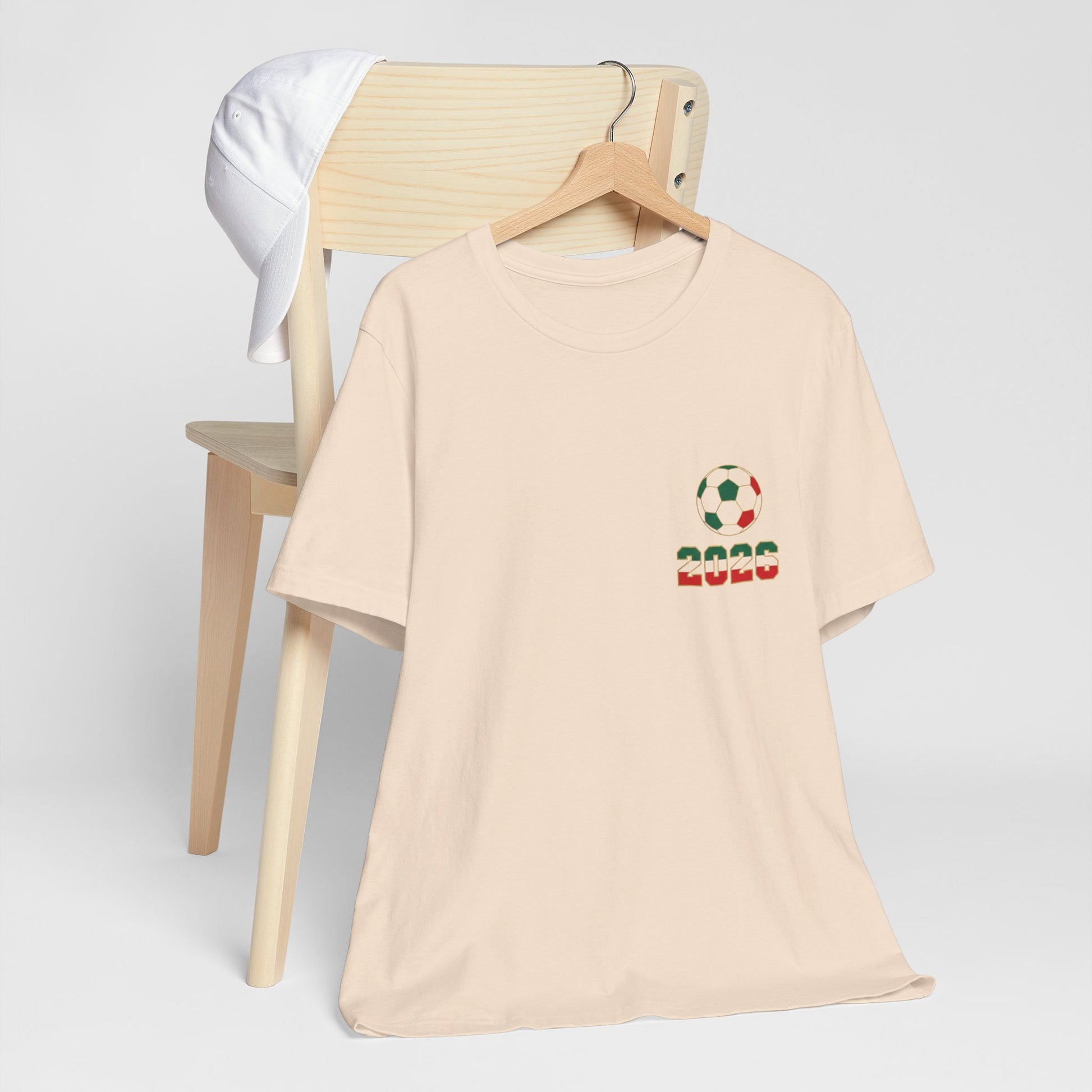 Soft cream El Tri soccer tee on hanger showing left chest logo, front view
