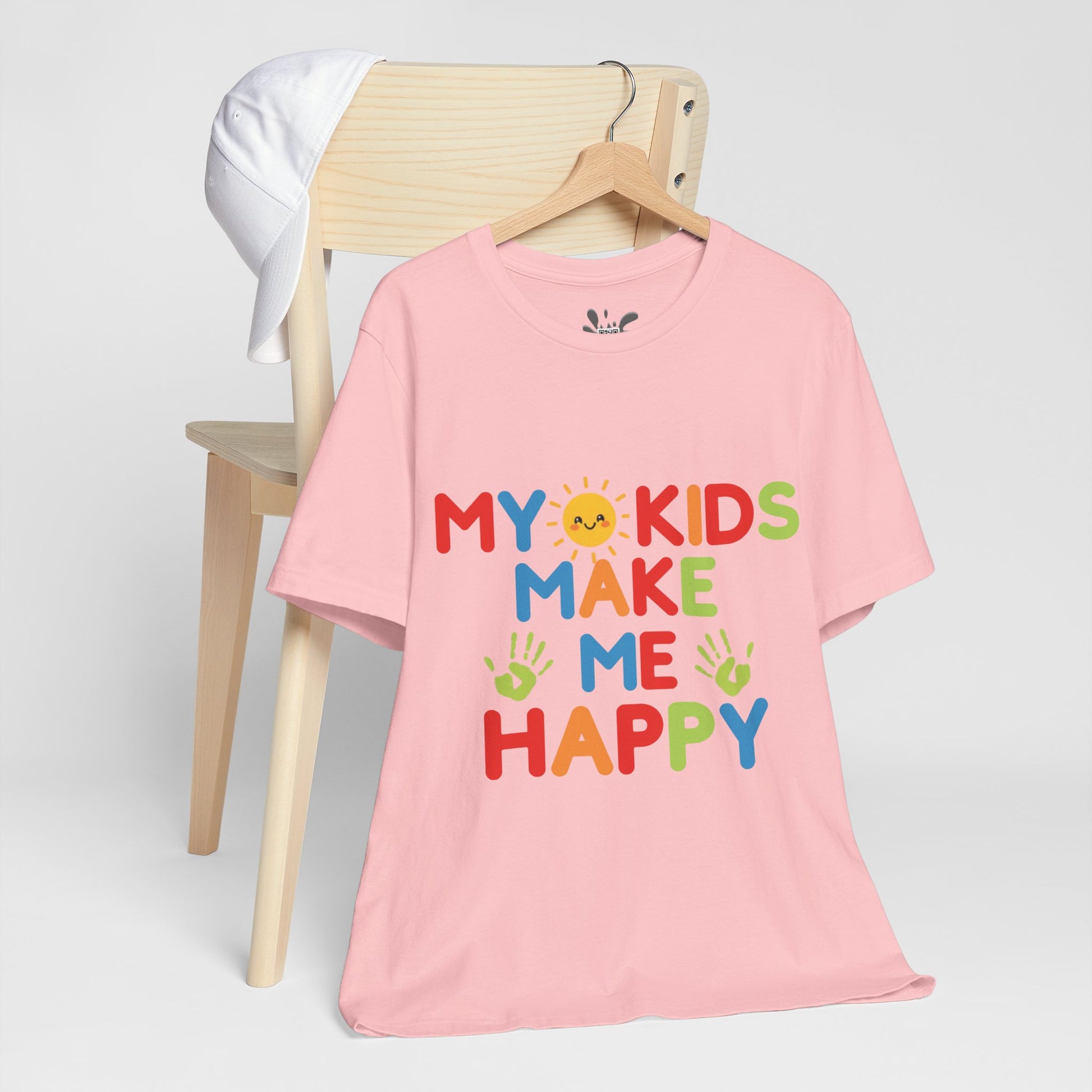 Pink t-shirt with 'My kids make me happy' text on a chair against a white background