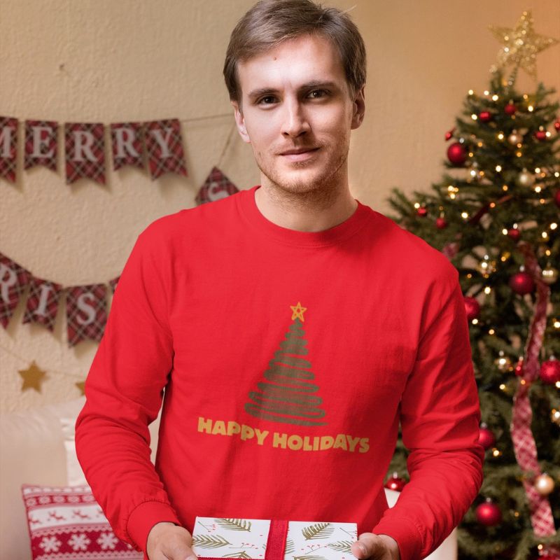 Model wearing the red “Happy Holidays” long-sleeve shirt in a Christmas-decorated room.