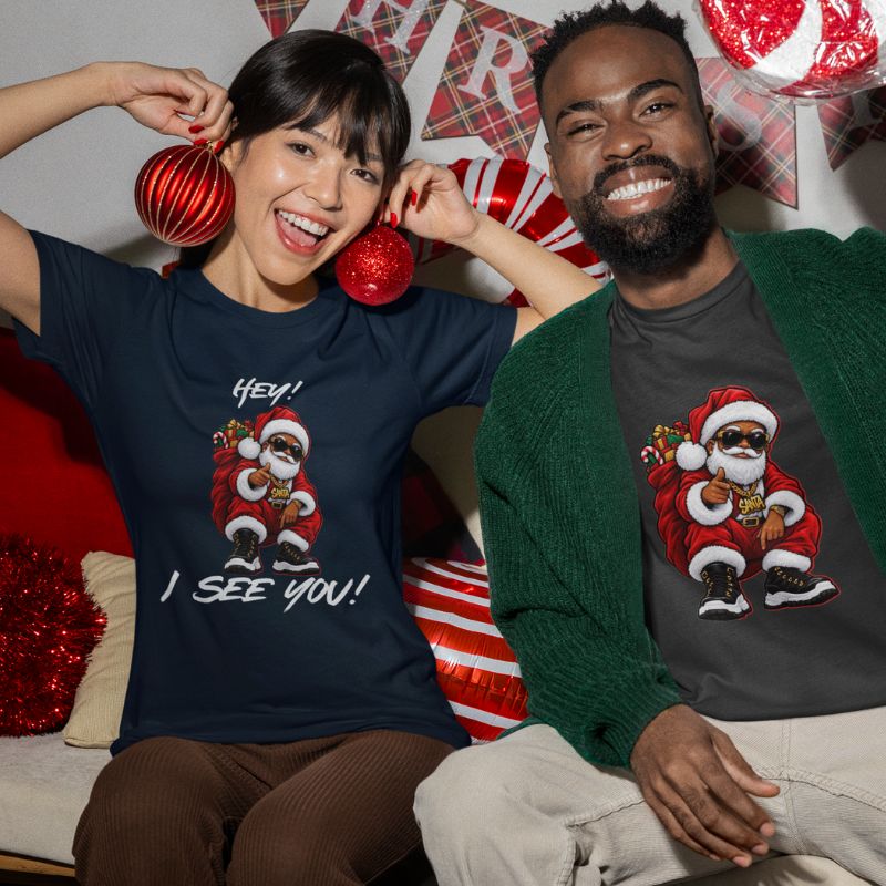 Two smiling people wearing navy and green Hey! I See You! Santa graphic t-shirts at a festive gathering.
