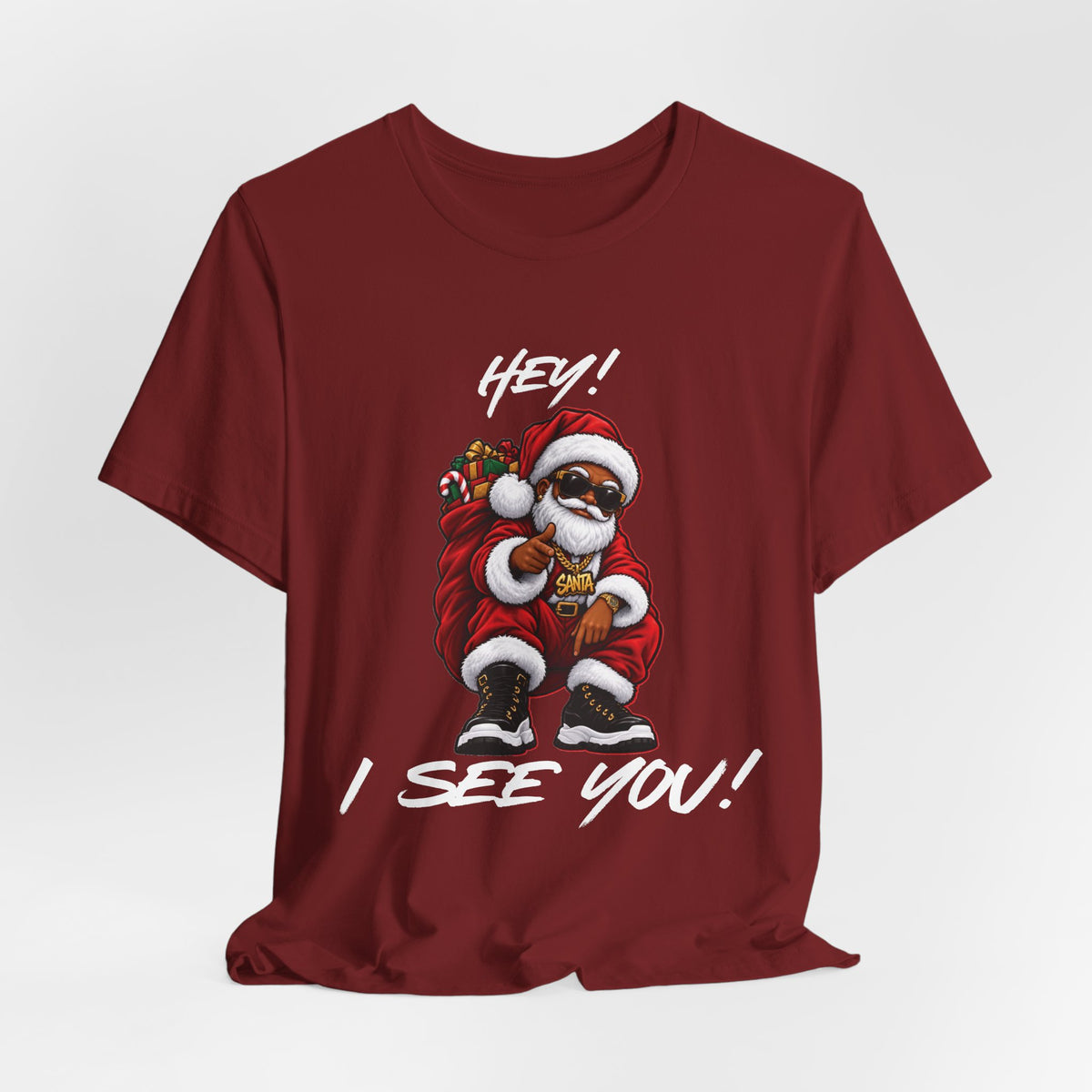 Front view of a burgundy Christmas t-shirt featuring Santa in sunglasses with the words Hey! I See You!
