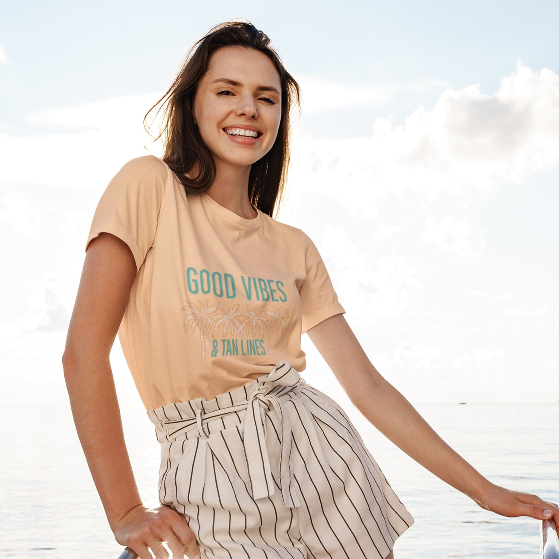 Woman wearing Good Vibes & Palm Lines peach graphic tee outdoors — Leela's Ink
