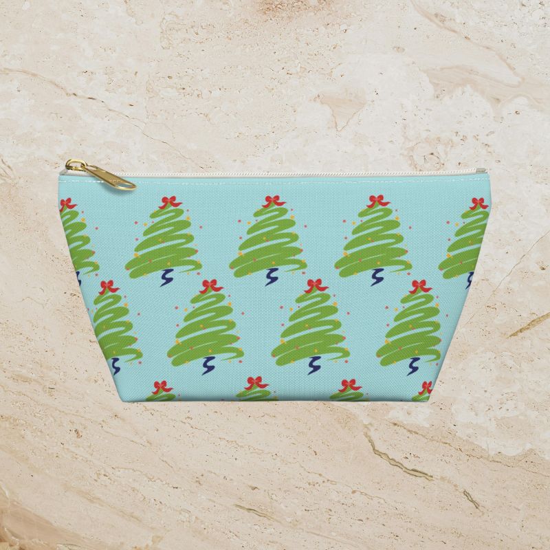 Front view of a small icy-blue accessory pouch with playful green Christmas trees and red accents.