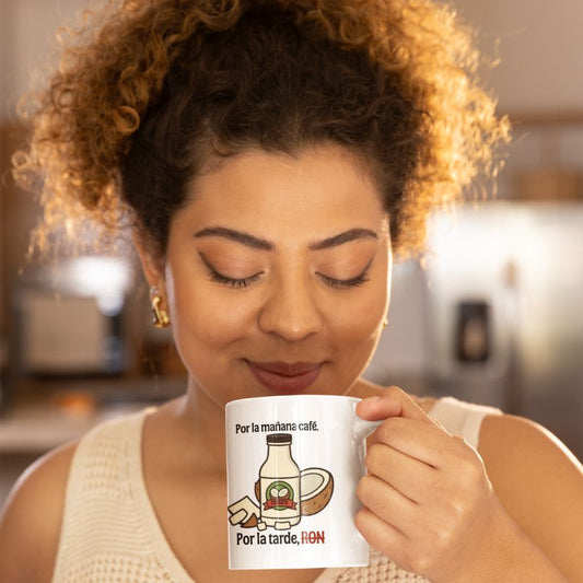 Woman holding a white “Por la mañana café. Por la tarde, RON” mug near her face.