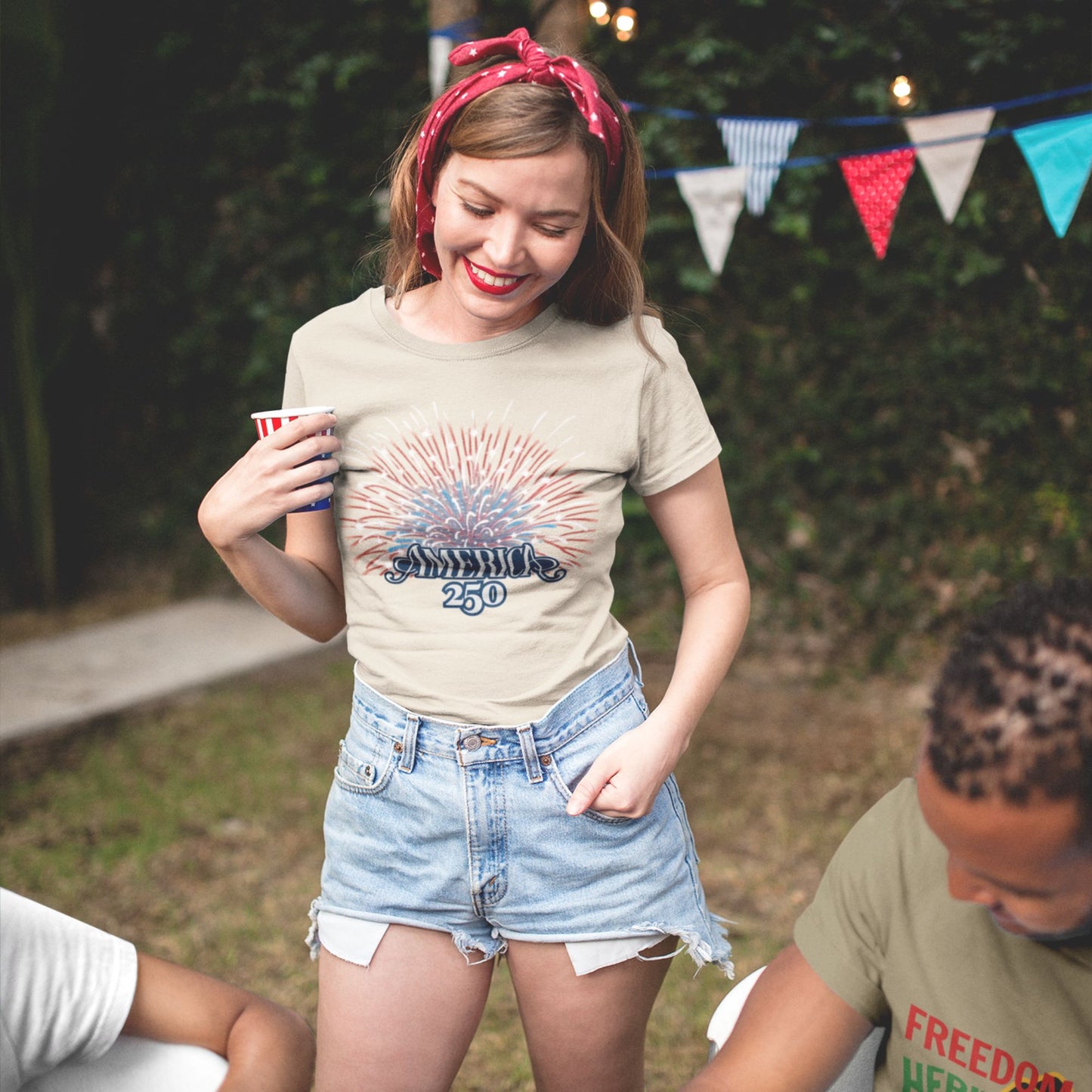 America 250 Fireworks Graphic Tee in Natural – woman at patriotic outdoor party wearing USA 250th anniversary fireworks tee


