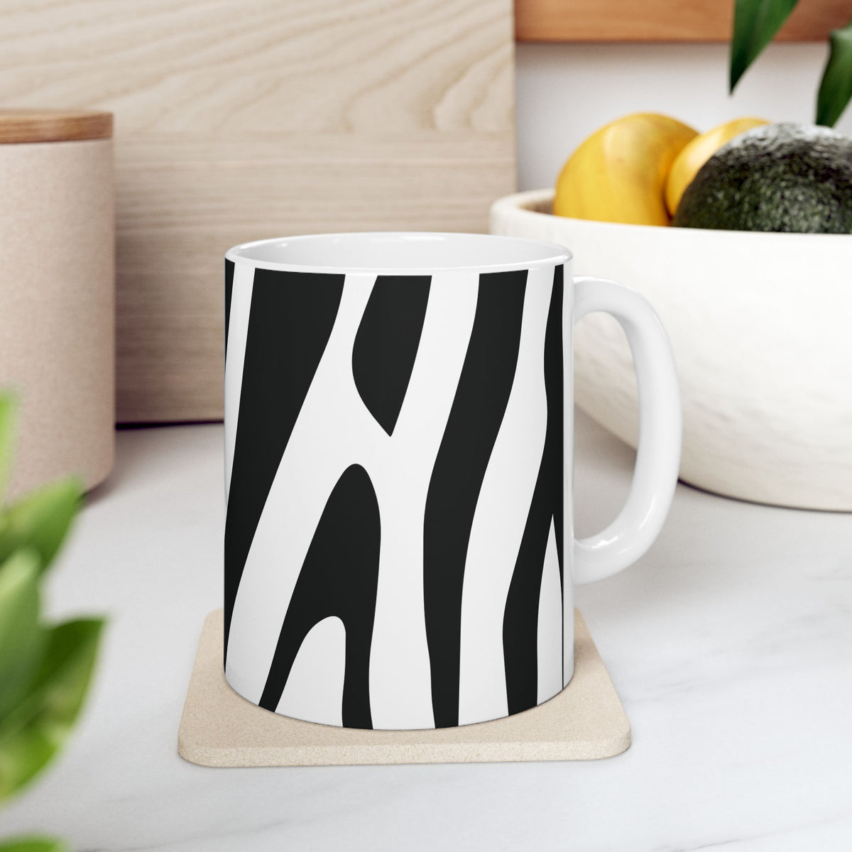 Black-and-white zebra print mug with a white handle on a coaster on a kitchen counter.