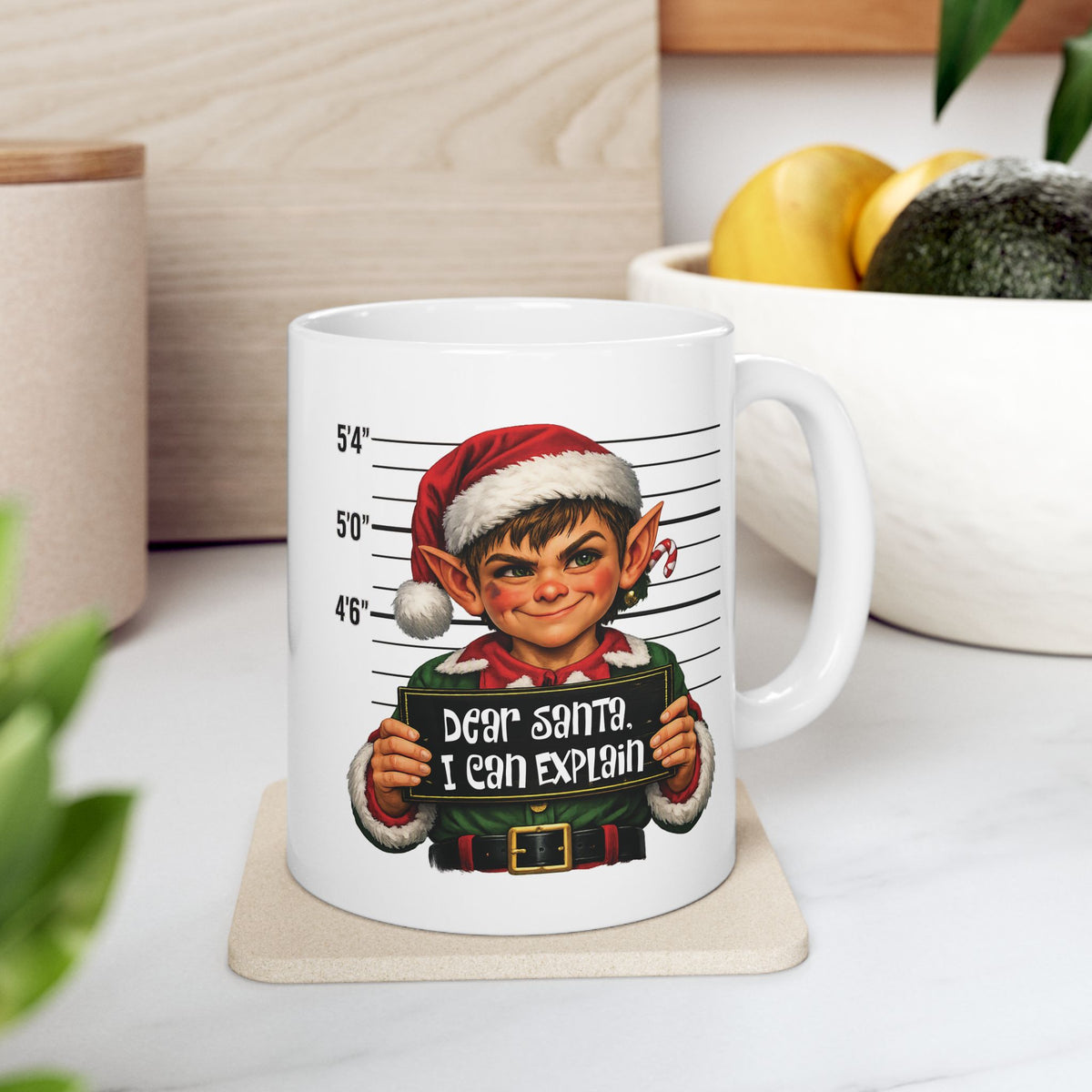 White Christmas mug featuring an elf holding a “Dear Santa, I can explain” sign on a kitchen counter.