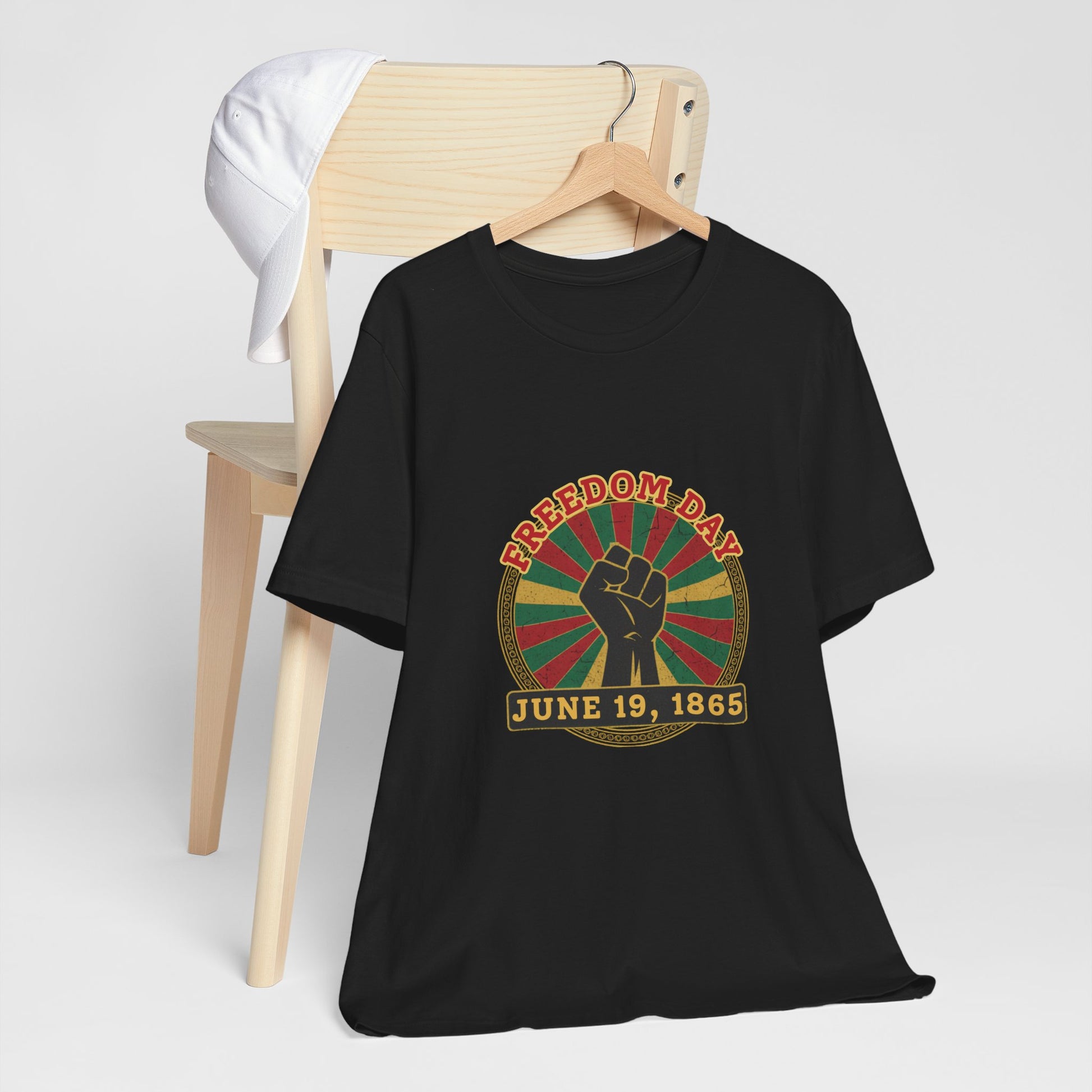 Freedom Day Juneteenth Tee in Black – flat hanger mockup showing raised fist sunburst June 19 1865 graphic

