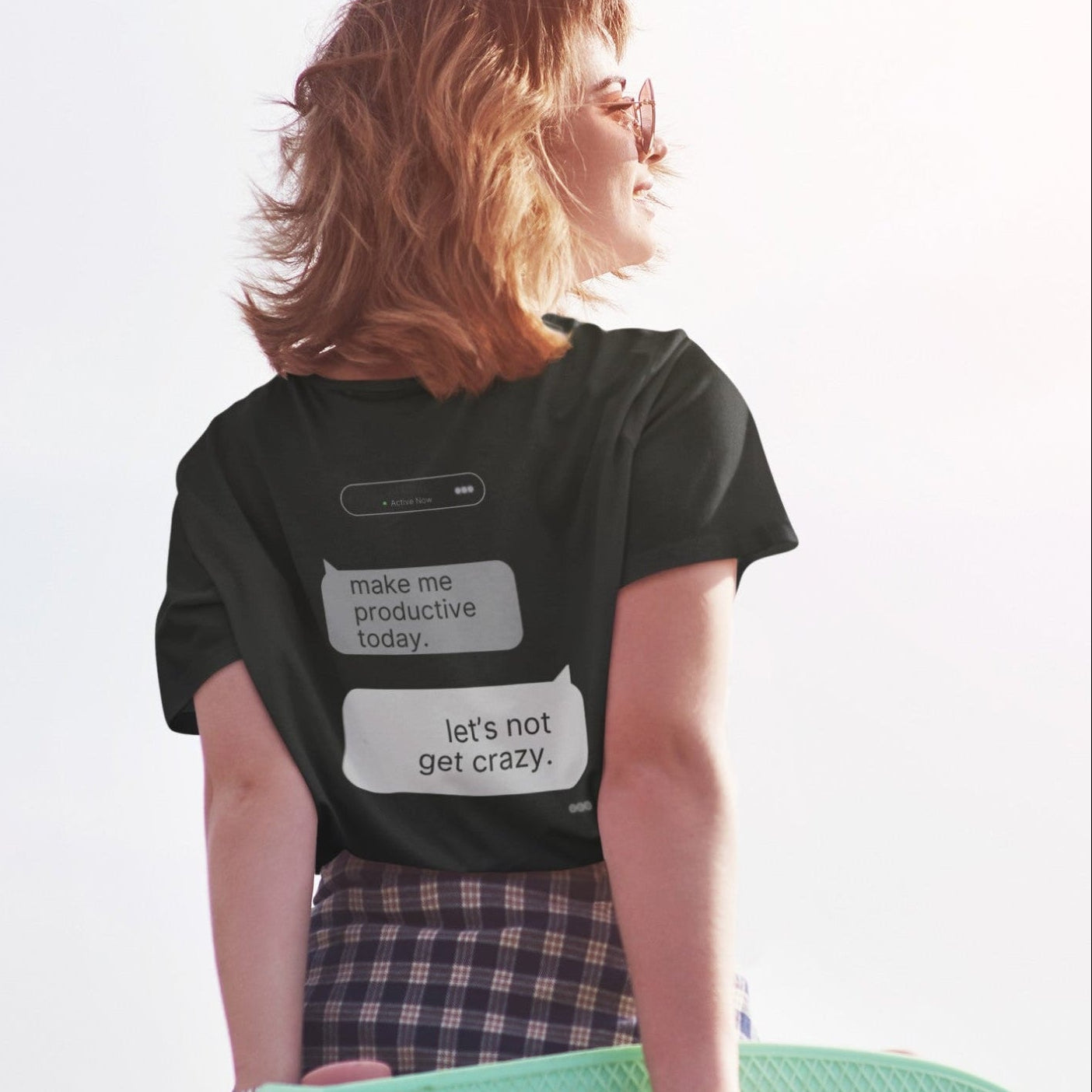Woman holding skateboard showing back print of Make Me Productive Today AI chat graphic tee in black
