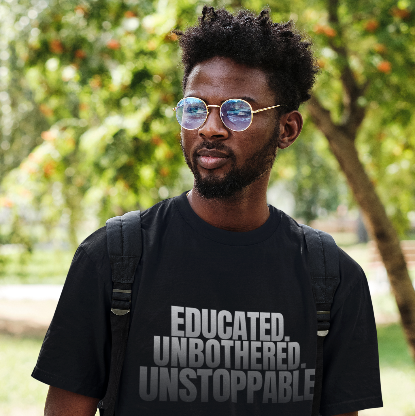Man wearing Educated Unbothered Unstoppable black graphic tee outdoors