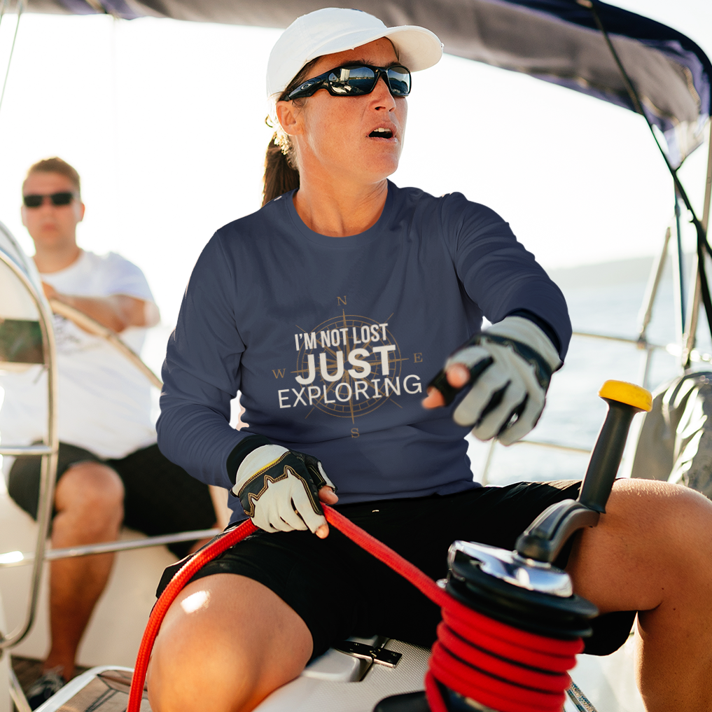 Man and woman on sailboat wearing navy I'm Not Lost Just Exploring long sleeve compass graphic tee — lifestyle shot
