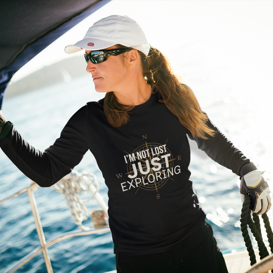 Woman wearing black I'm Not Lost Just Exploring long sleeve compass tee on a sailboat — lifestyle shot

