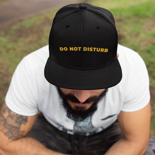 Do Not Disturb embroidered snapback dad cap in black with neon yellow lettering — worn by tattooed male model in casual white tee