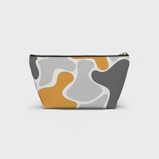 Product slideshow of a yellow, gray, and white abstract camo accessory pouch with a black zipper and gold-tone pull, displayed against a white background.
