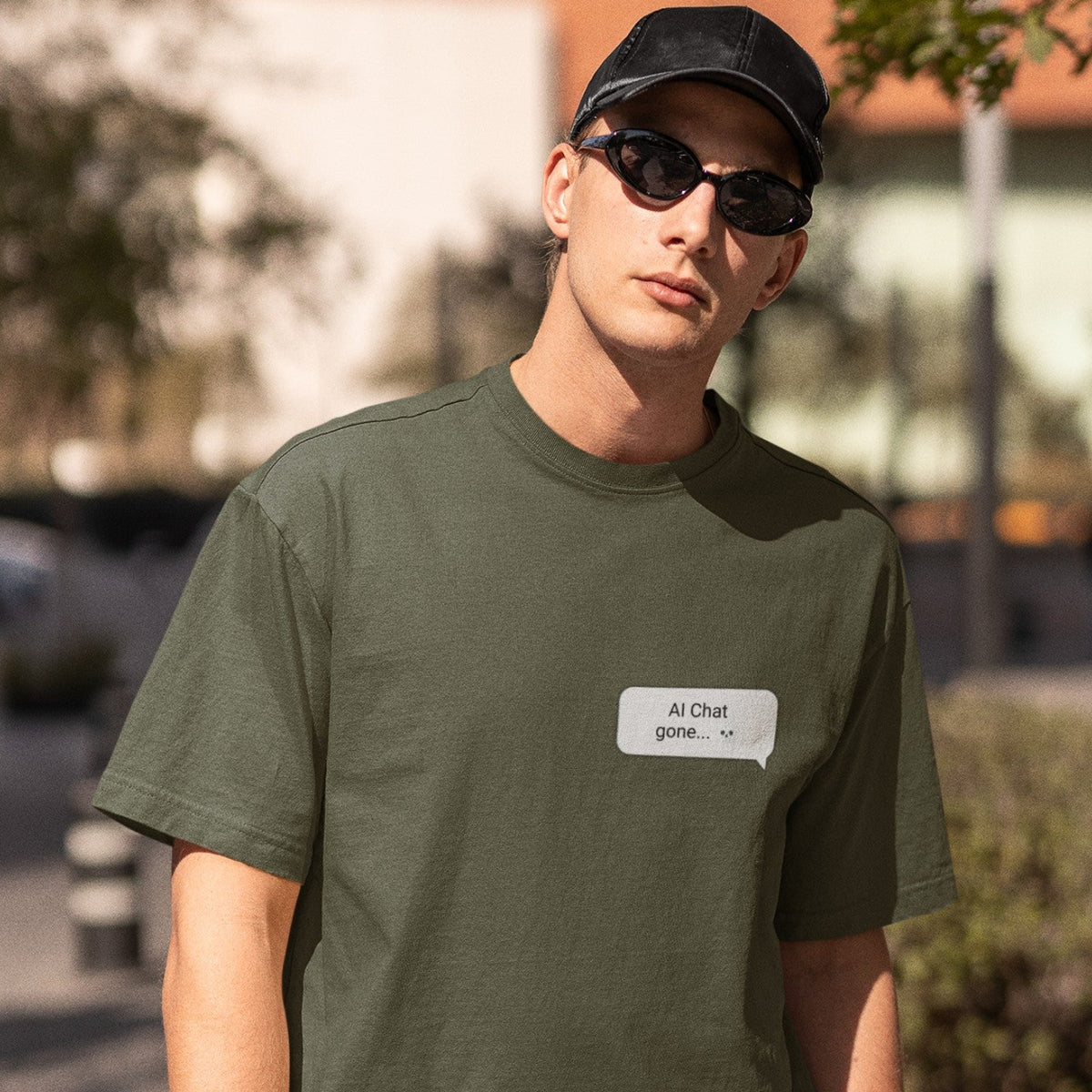 Man in sunglasses wearing Is This a Good Idea graphic tee in military green with left chest chat bubble print
