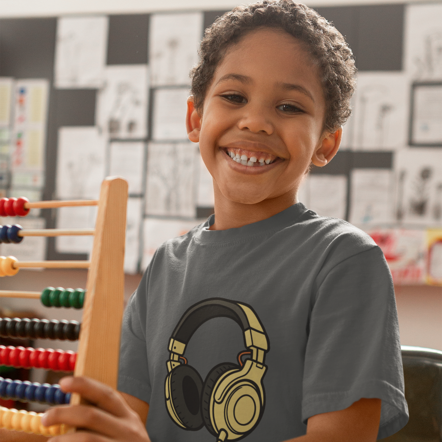 Boy wearing Kids Headphones Graphic T-Shirt in Athletic Heather, classroom lifestyle shot